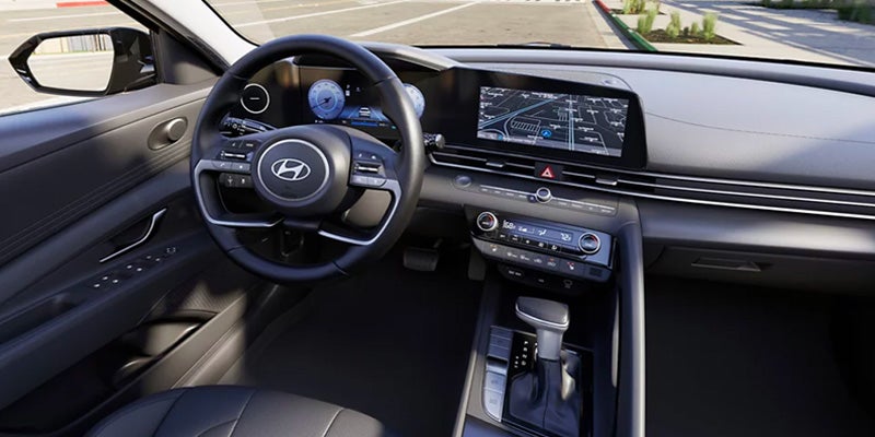 Interior view of car dashboard, steering wheel, and digital infotainment screen.