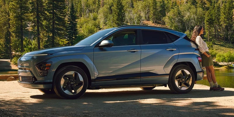 Side profile of a blue SUV parked in a wooded area.