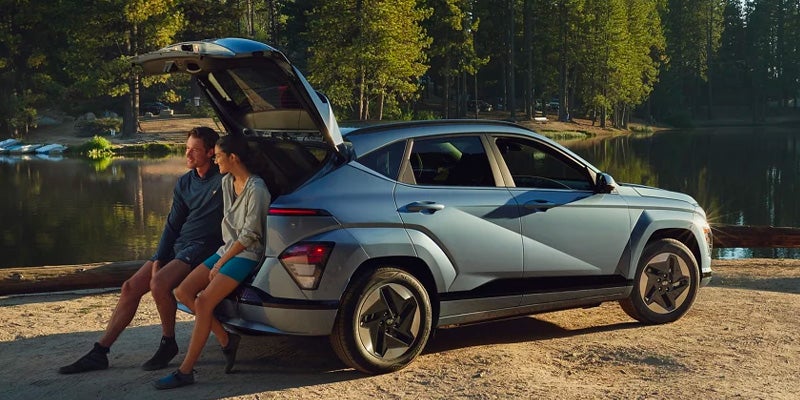 People sitting in the open trunk of a blue SUV.