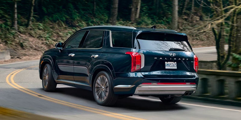 Rear three-quarter view of a dark blue Hyundai Palisade on the road.