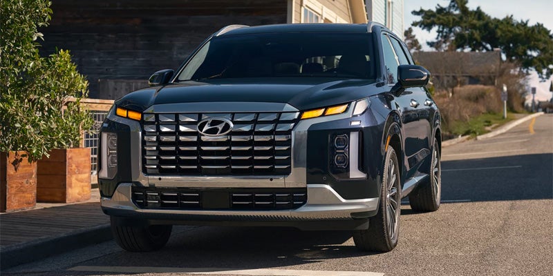 Close-up of the front grille and headlights of a blue Hyundai Palisade.