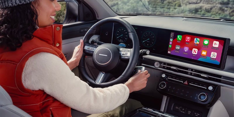 A driver using the steering wheel and digital console inside the car.
