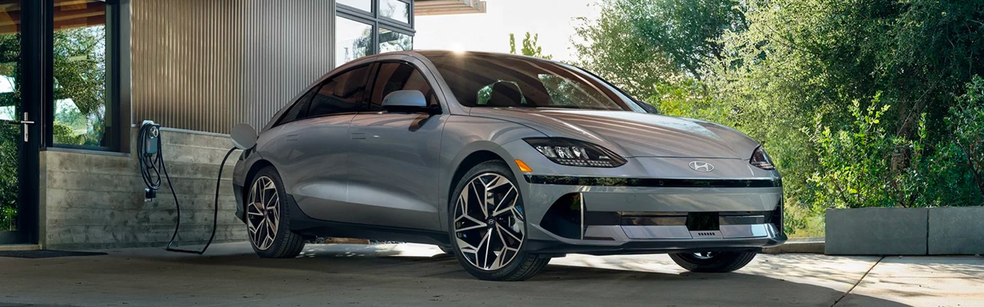 A silver Hyundai IONIQ 6 electric sedan charging at a modern home.