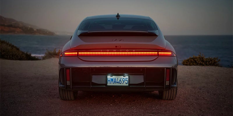Rear view of a gray Hyundai IONIQ 6 with illuminated taillights.