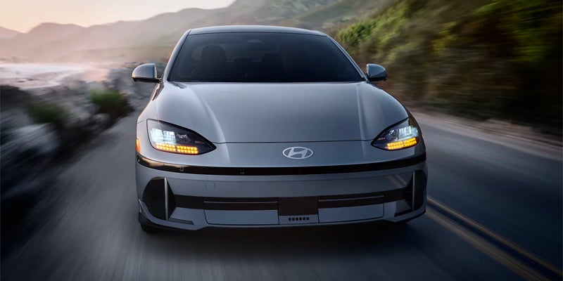 Front view of a gray Hyundai IONIQ 6 driving on a road.