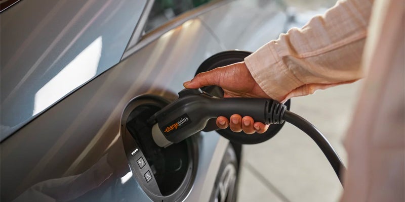 Close-up of an electric vehicle charging cable being plugged in.