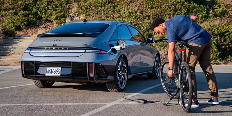 A person standing by a Hyundai IONIQ 6 in a parking lot