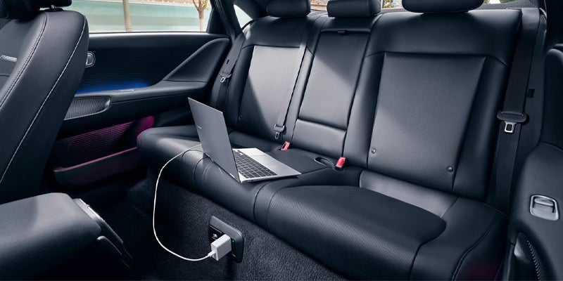 Rear passenger seats of a vehicle with a laptop plugged in.