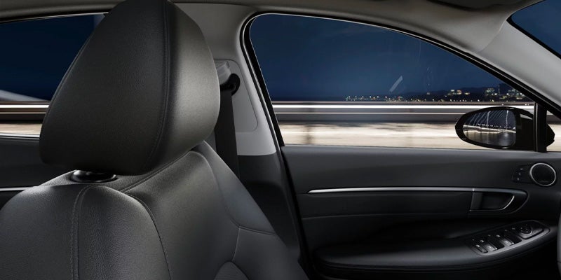 Close-up of a black leather car seat and side window