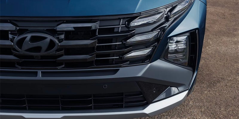 Close-up of a blue Hyundai's front grille and headlight assembly