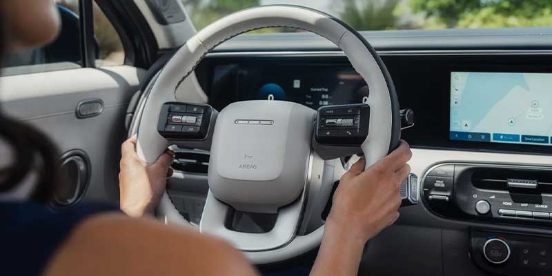 Close-up of hands on the steering wheel with digital displays.